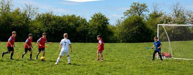 Children playing football on the field at a SupaFit session