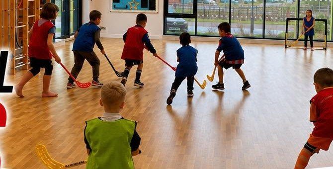 Children playing hockey in the sports hall at an after school club
